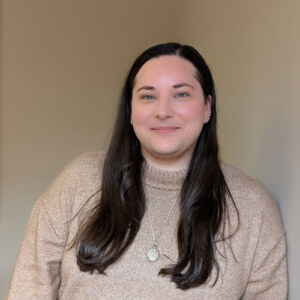 Woman with straight, long, dark hair wearing a light beige sweater.