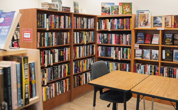 A library with filled bookshelves and a wooden table with a chair